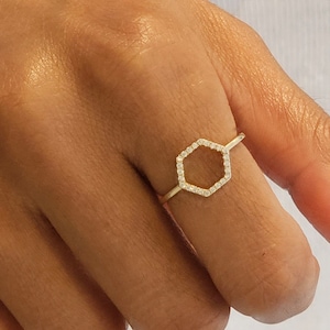 May include: A gold ring with a hexagon-shaped design. The hexagon is outlined with small diamonds.