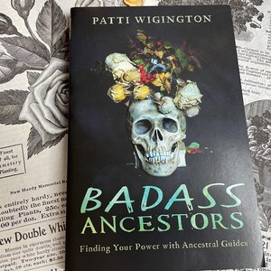 Könnte beinhalten: Ein Buch mit dem Titel "BADASS ANCESTORS" von Patti Wigington. Das Cover zeigt einen mit Blumen geschmückten Schädel vor schwarzem Hintergrund. Vintage botanische Illustrationen und Text sind im Hintergrund zu sehen.