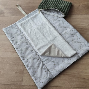 Può includere: Un set per fasciatoio per bambini con motivo floreale, un asciugamano in spugna bianco e una pochette in velluto a coste verde. Il fasciatoio è grigio chiaro con un design trapuntato.