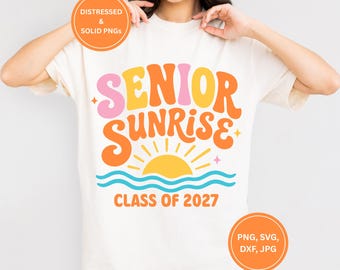 Könnte beinhalten: Cremefarbenes T-Shirt mit den Worten "SENIOR SUNRISE" in Orange, Gelb und Rosa, mit einer Sonne und Wellen Grafik. Der Text "CLASS OF 2027" steht darunter. Zwei orangefarbene Kreise mit Text sind im Bild.