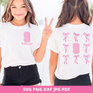 May include: White t-shirt with a pink number 9 and the text "Birthday Girl" on the front. The back of the shirt features a pink number 9 and pink bows. The shirt is worn by a person.
