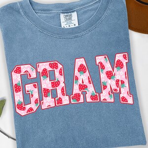 Strawberry-themed retro varsity style Mother's Day PNG shirt designs for sublimation, featuring Mama, Momma, Mini, Gigi, Gram, and Lita in pink red floral fruit print on white t-shirts, digital files for Cricut and heat press crafting, perfect for Mother's Day gifts and matching family outfits on Etsy.