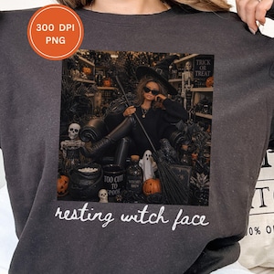 May include: A dark grey sweatshirt featuring a graphic print of a doll dressed as a witch in a black hat and sunglasses, sitting in a chair surrounded by pumpkins, skulls, and a cauldron. The text "resting witch face" is printed below the image.