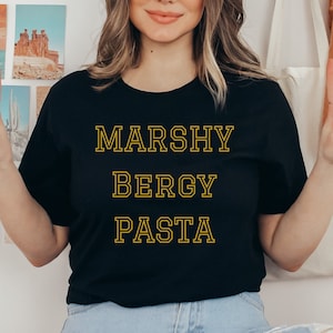 May include: A black t-shirt with the text "MARSHY BERGY PASTA" in yellow outlined letters.