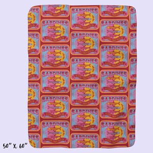May include: A red and blue patterned fabric with a repeating design of sardine cans. Each can has a label that reads "Sardines in Extra Virgin Olive Oil".