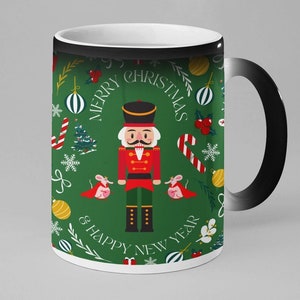May include: A black and white color changing mug with a green background. The mug features a Nutcracker, two mice, candy canes, ornaments, and the text "Merry Christmas & Happy New Year".
