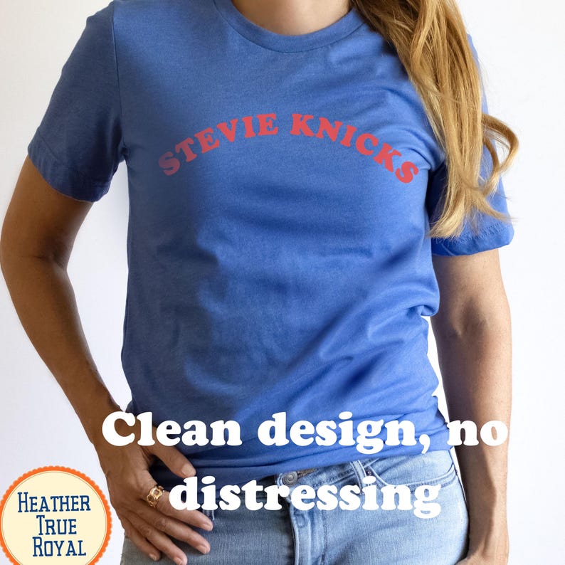 Puede incluir: Una camiseta de manga corta en color azul real jaspeado con el texto STEVIE NICKS en una fuente roja, arqueada y sin remates en el pecho. La prenda tiene cuello redondo y un dise&ntilde;o limpio, sin ning&uacute;n tipo de desgaste en la tela.