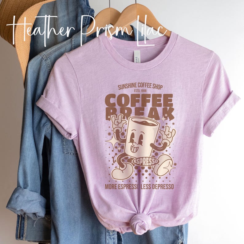 May include: A heather prism lilac t-shirt with a retro-style coffee cup graphic. The graphic says "Sunshine Coffee Shop Est. 1956 Coffee Break" and "More Espresso Less Depresso".