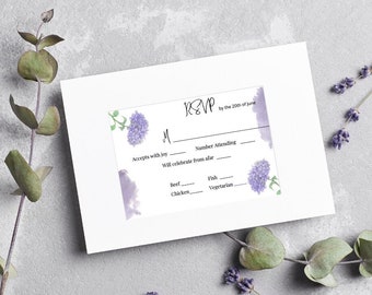 May include: RSVP card with a watercolour design of purple flowers. The card has fields for the guest's name, number attending, meal choice, and RSVP deadline. The text reads "RSVP by the 20th of June".