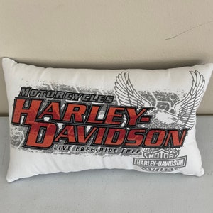 K&ouml;nnte beinhalten: Ein wei&szlig;es Kissen mit einem roten und grauen Harley-Davidson-Logo. Das Logo lautet "Motorcycles Harley-Davidson Live Free-Ride Free Motor Harley-Davidson Cycles".