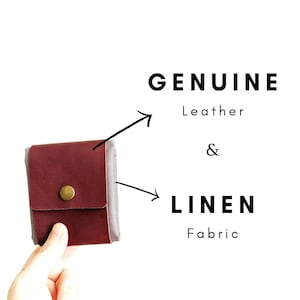 May include: A small, burgundy leather wallet with a brass snap closure. The wallet is made of genuine leather and linen fabric. The text "GENUINE Leather & LINEN Fabric" is displayed.