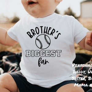 Peut inclure: Un body b&eacute;b&eacute; blanc avec un texte noir qui dit "Brother's Biggest Fan" avec un graphique de baseball. Le texte "Personnalis&eacute; : Papa, Oncle, S&oelig;ur, Bubba, Maman ETC..." est &eacute;crit en noir dans le coin inf&eacute;rieur droit du body b&eacute;b&eacute;.
