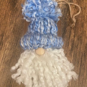 May include: A blue and white yarn gnome ornament with a white yarn beard and a wooden nose.