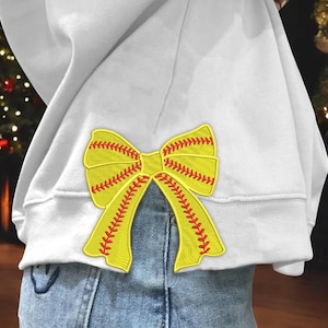 Peut inclure: Un sweat-shirt blanc avec un nœud jaune et rouge sur le thème du softball cousu sur le dos.