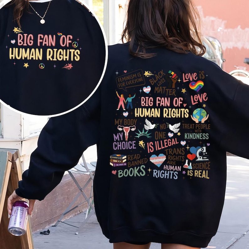 May include: Black sweatshirt with the text "BIG FAN OF HUMAN RIGHTS" in colorful lettering. The back of the sweatshirt features various graphics and phrases, including "Feminism is for Everyone," "Black Lives Matter," and "Love is."
