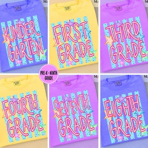 Könnte beinhalten: Eine Kollektion von sechs T-Shirts in Gelb, Lila und Lavendel, jeweils mit vertikalen blaugrünen Streifen mit schwarzen Punkten und rosa Sternen. Die T-Shirts zeigen einen rosa Schriftzug mit den Aufschriften Kinder Garten, First Grade, Third Grade, Fourth Grade, Seventh Grade und Eighth Grade.