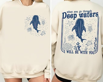 May include: Cream-colored sweatshirt with a blue whale and sea creature graphic. The front features a whale, starfish, jellyfish, and turtle. The back has the text "When you go through Deep waters, I will be with you."