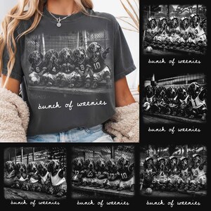 Puede incluir: Camiseta gris oscuro con una imagen en blanco y negro de perros salchicha con uniformes deportivos. El texto "bunch of weenies" está escrito en una fuente manuscrita. Los perros llevan camisetas con números.
