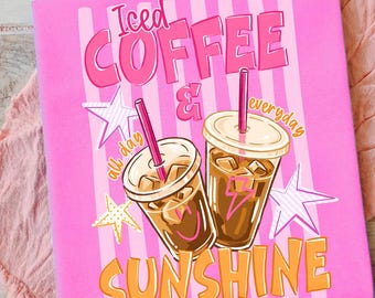 May include: Pink notebook featuring the text "Iced Coffee & Sunshine". The design includes illustrations of two iced coffee cups with straws, stars, and the words "all day" and "everyday". The background has vertical stripes.