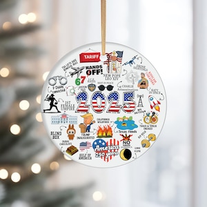 Puede incluir: Un adorno navideño redondo y blanco, con una cuerda dorada para colgar. El adorno presenta el año "2025" en rojo, blanco y azul, rodeado de varias ilustraciones y texto, incluyendo "America 250 years".