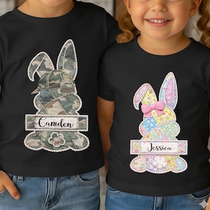 May include: Black t-shirts with a bunny design. One bunny is in camouflage, the other in floral patchwork. Each has a name tag: "Camden" and "Jessica". A cute Easter-themed design.