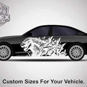 May include: Black car with a white Godzilla decal on the side. The decal features a detailed illustration of Godzilla's head and body. The image includes the text "Custom Sizes For Your Vehicle."