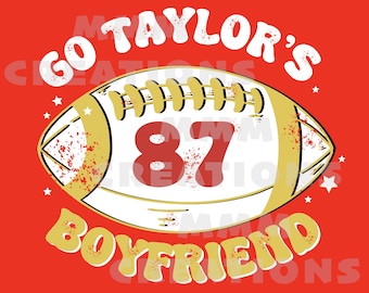 May include: A red background with a white football with a gold outline and the number 87 in red. The text "Go Taylor's Boyfriend" is in gold around the football.