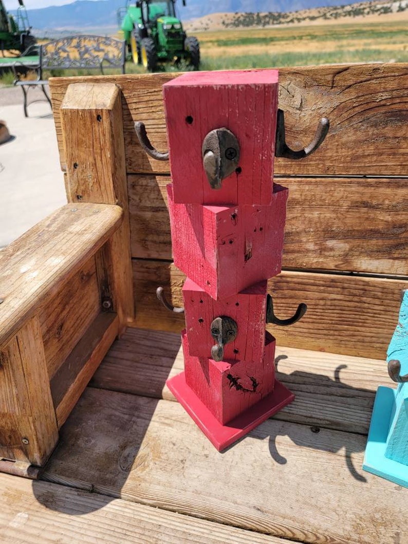 Op de afbeelding: Een rode houten kapstok met drie lagen haken. Elke laag heeft twee haken. De kapstok is gemaakt van gerecycled hout en heeft een rustieke uitstraling.