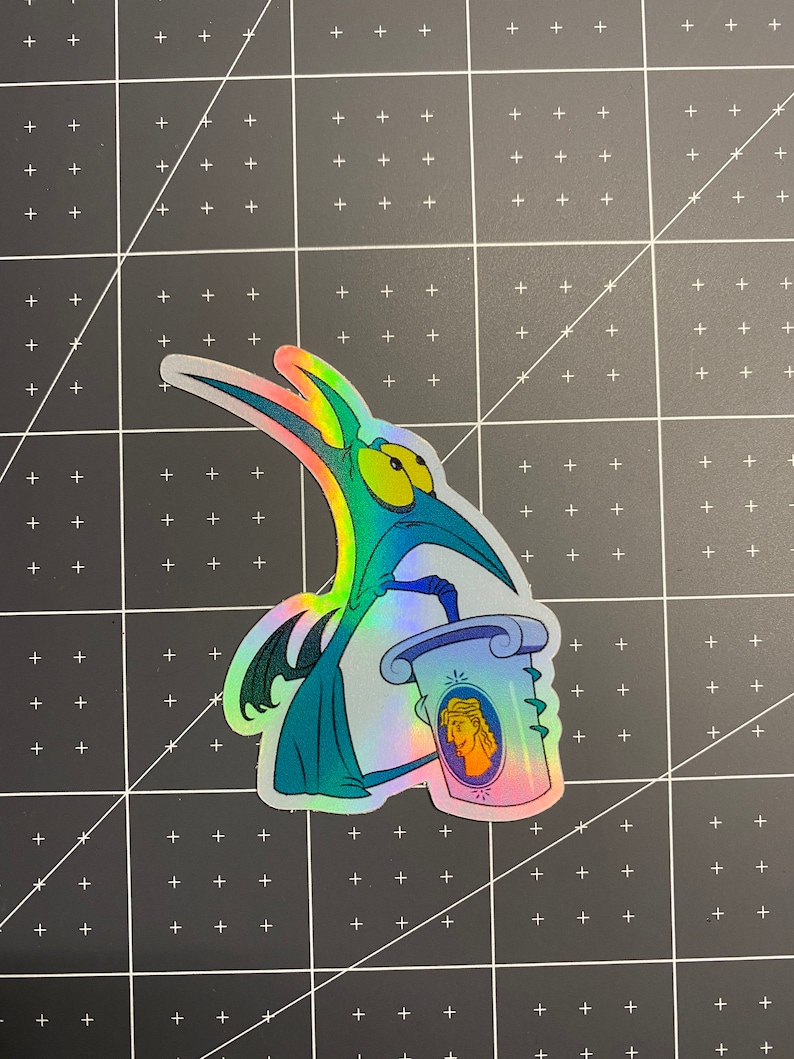 May include: A holographic sticker featuring a cartoon character with a long beak and teal body. The character holds a scroll with a portrait of a person. The sticker has a rainbow sheen and is set against a black grid background.