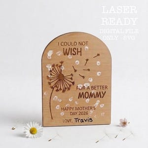May include: Wooden plaque with a dandelion design and the text "I COULD NOT WISH FOR A BETTER MOMMY HAPPY MOTHER'S DAY 2026 LOVE, Travis". The plaque is light brown with white accents.