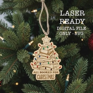 Puede incluir: Adorno navideño de madera con forma de árbol de libros, con una estrella en la parte superior. El texto "ALL BOOKED FOR CHRISTMAS" está en el adorno. Cuelga de un árbol de Navidad. Listo para láser.