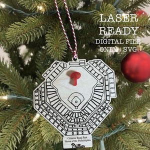 May include: A wooden Christmas ornament shaped like Citizens Bank Park, home of the Philadelphia Phillies, with a red accent. The ornament is laser-ready and a digital SVG file. The ornament hangs on a Christmas tree.