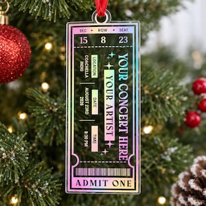 May include: A rectangular, clear acrylic ornament shaped like a concert ticket with a holographic finish. It features text including "YOUR CONCERT HERE," "YOUR ARTIST," "COACHELLA INDIO," "AUGUST 23RD 2026," "8:30 PM," "ADMIT ONE," and a barcode.