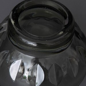 May include: A black glass bowl with a decorative pattern of leaves around the rim. The bowl has a smooth, shiny finish.