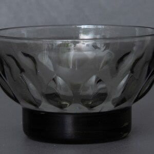 May include: A clear glass bowl with a textured, leaf-like pattern. The bowl has a black base.