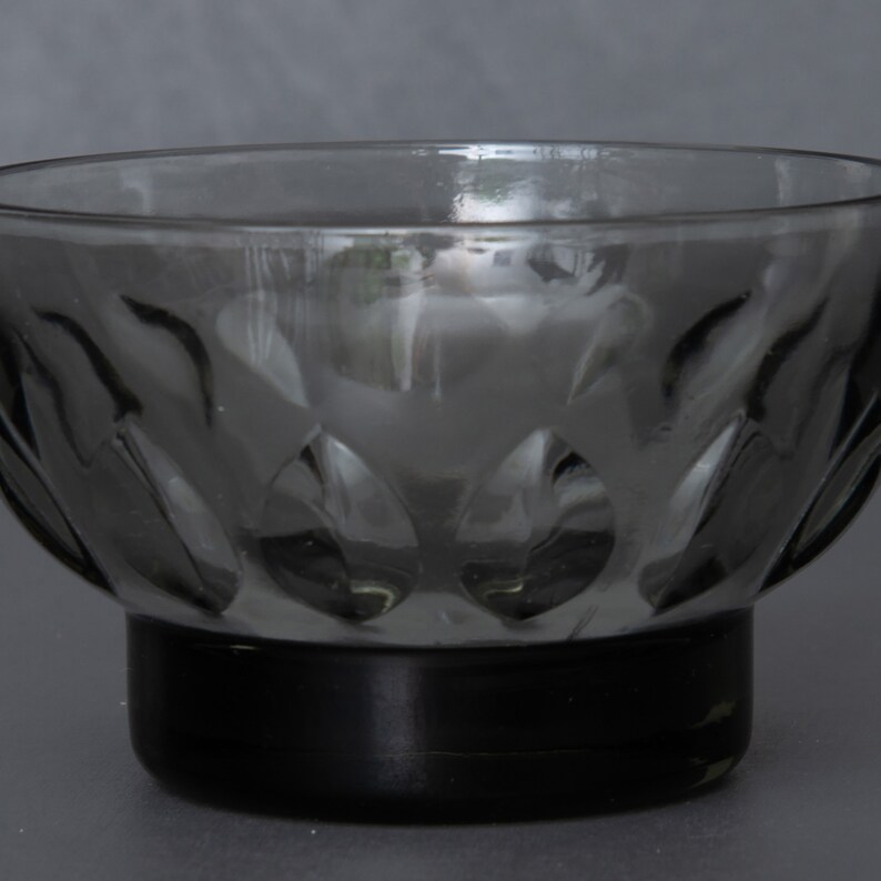 May include: A clear glass bowl with a textured, leaf-like pattern. The bowl has a black base.