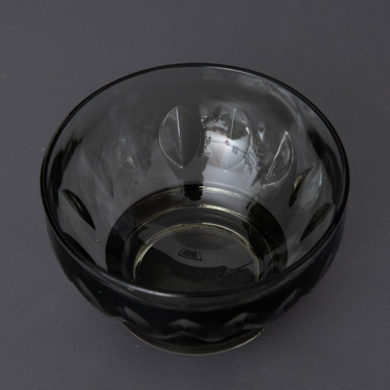 May include: A clear glass bowl with a scalloped rim and a textured pattern. The bowl is empty and has a slight green tint.