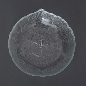 May include: A clear glass bowl with a leaf design. The bowl is round and has a textured surface.