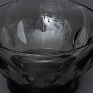 May include: A dark grey glass bowl with a textured, faceted design. The bowl is empty and has a reflective surface.