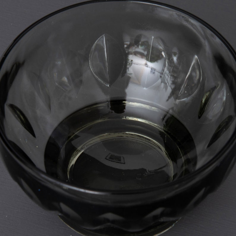 May include: A clear glass bowl with a scalloped rim and a textured bottom. The bowl is empty and has a slight green tint.