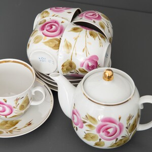 May include: A white porcelain tea set with pink and green floral designs. The set includes a teapot, four teacups, and saucers.