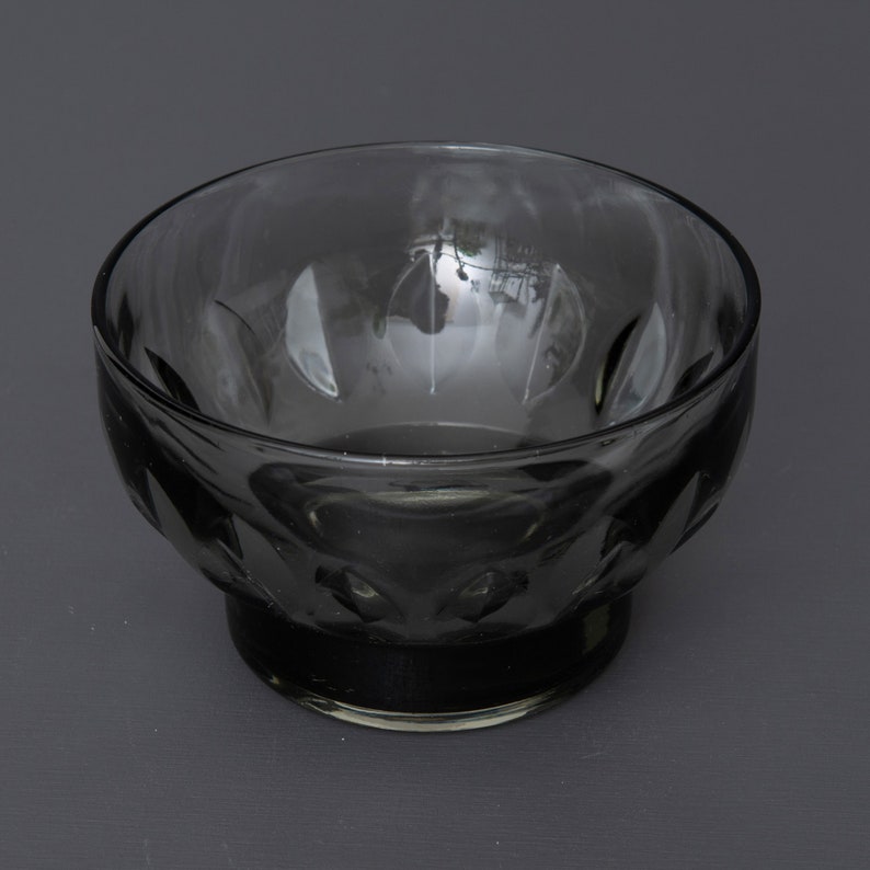 May include: A clear glass bowl with a textured, diamond-shaped pattern. The bowl is dark grey in colour and has a wide, round base.