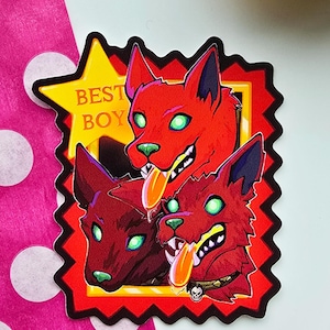 May include: A sticker depicting three cartoon dogs with red fur, green eyes, and tongues extended. The sticker has a yellow star with the words "BEST BOY" and a red, jagged border. The dogs have a skull collar.