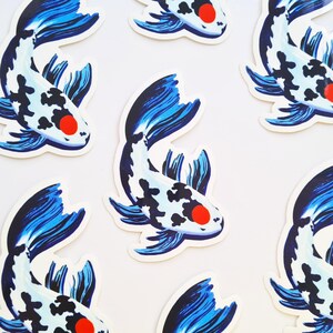 May include: A collection of stickers featuring a koi fish design. The fish have a white body with black spots, blue fins and tail, and a red eye. The stickers are arranged on a white background.