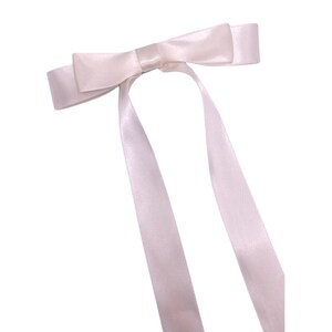 May include: A white satin ribbon bow with two long tails.