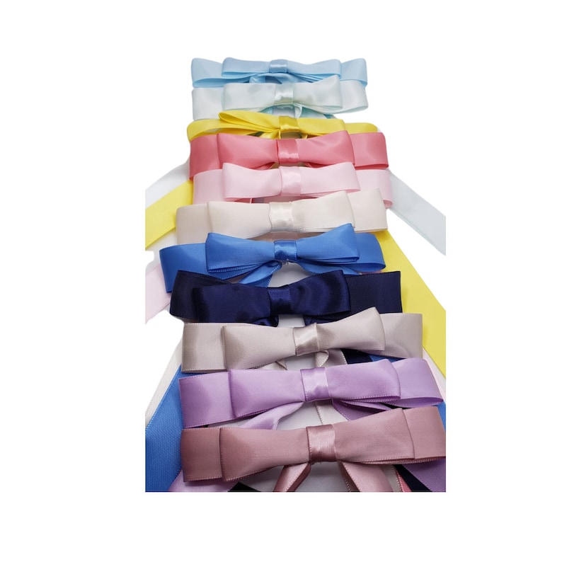 May include: A stack of 10 satin ribbon bows in various colours, including light blue, yellow, pink, white, blue, navy, grey, lavender, and mauve.