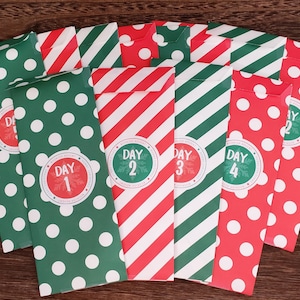May include: Twelve red and green paper bags with white polka dots and stripes. Each bag has a red circle with the words "Day" and a number from 1 to 12.