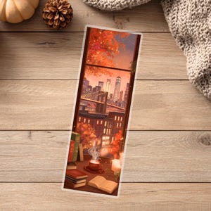 Peut inclure: Marque-page avec une illustration d'un paysage urbain vu &agrave; travers une fen&ecirc;tre. L'&oelig;uvre repr&eacute;sente une sc&egrave;ne chaleureuse avec des livres, une tasse de caf&eacute; et une bougie allum&eacute;e, &eacute;voquant une ambiance automnale.
