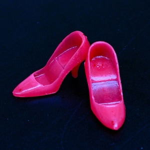 Peut inclure: Une paire de chaussures à talons hauts de couleur rose vif en plastique. Les chaussures sont pointues et ont un design simple.