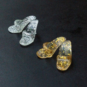 May include: Two pairs of sparkly sandals. One pair is silver and the other is gold.